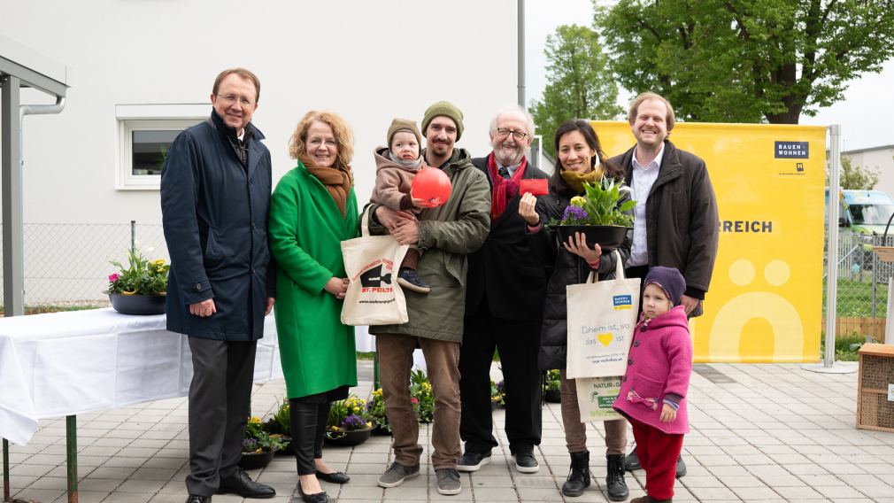 Ein Gruppenfoto mit Vertretern der Wohnungsgenossenschaft, der Politik und einer Familie, die in ihr neues Zuhause einzieht.