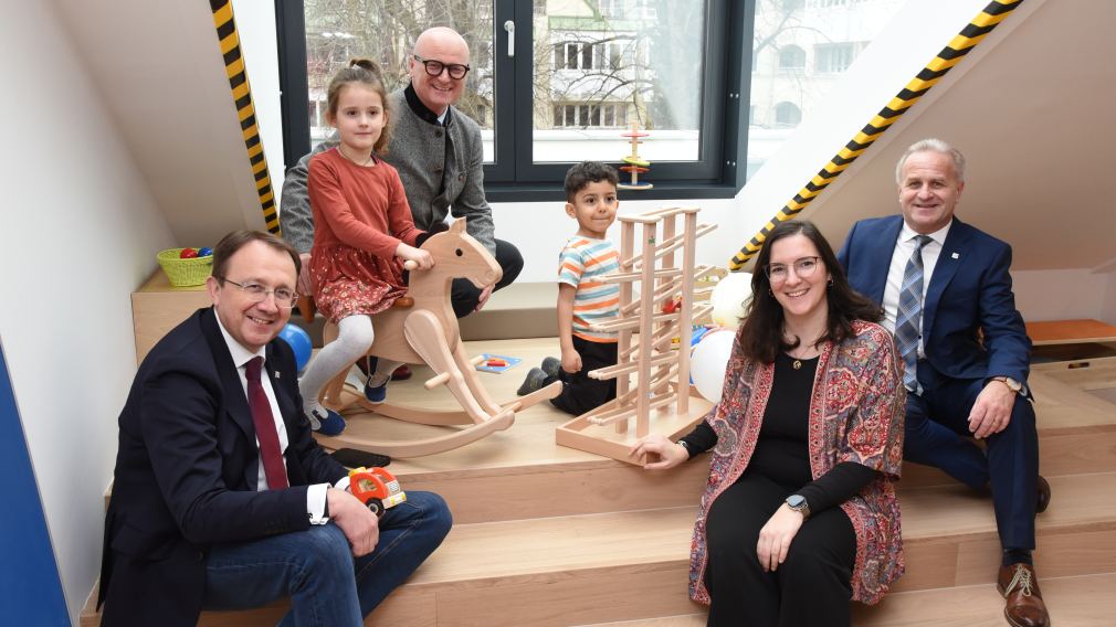 Bürgermeister Matthias Stadler, Baumeister Markus Steinwendtner, Kindergartenleiterin Marion Gnigler und Schulamtsleiter Andreas Schmidt sitzen im neuen Kindergarten mit zwei Kindern. (Foto: Vorlafuer)