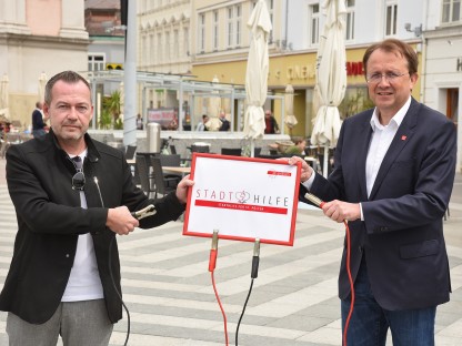 Bürgermeister Matthias Stadler und Michael Bachel vom Wirtschaftsservice mit Schild am Rathausplatz. (Foto: Vorlaufer)