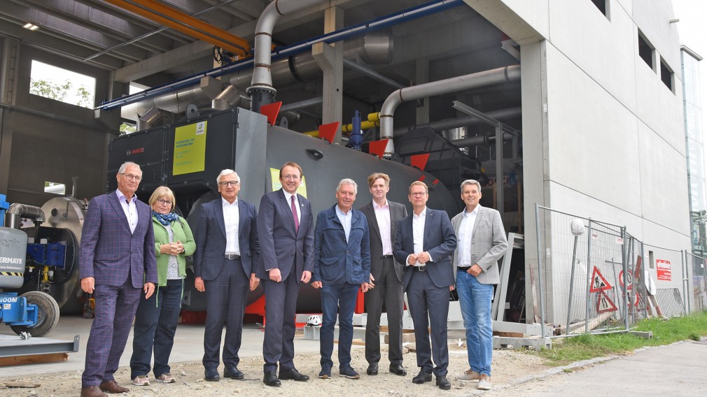 Geschäftsführer und ProkuristInnen der Fernwärme, EVN Vorstandsmitglieder und der Vizepräsident der EVN bei einem Gruppenfoto. Im Hintergrund sieht man die neue Anlage des FHK Nord in St. Pölten