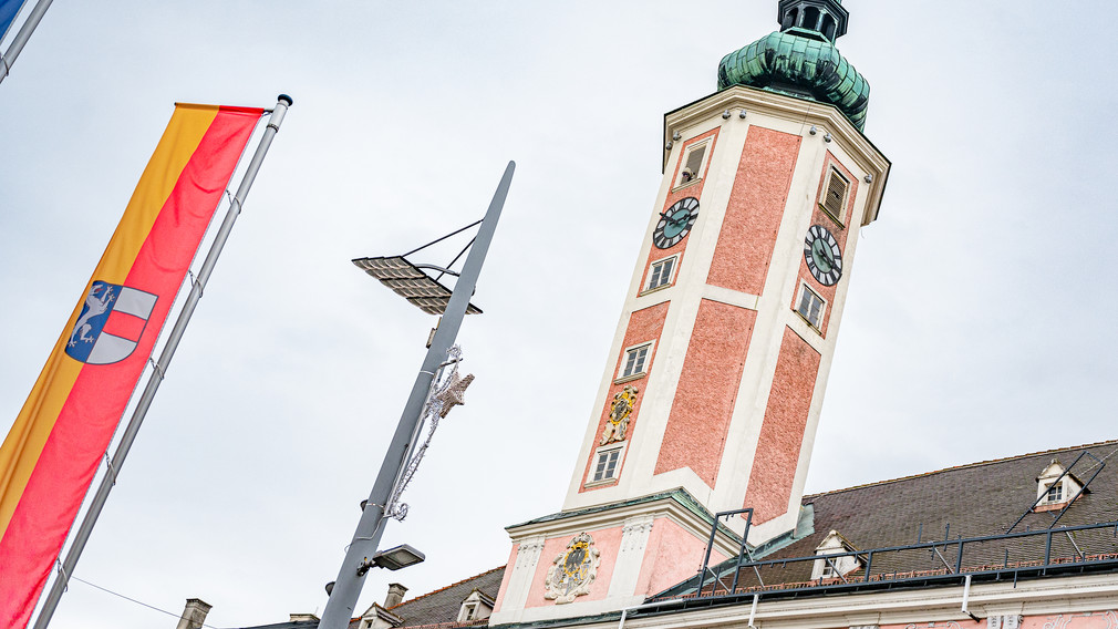 Der Rathausturm in St. Pölten mit einer Stadtfahne im Vordergrund.