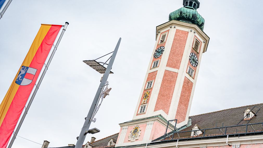 Der Rathausturm in St. Pölten mit einer Stadtfahne im Vordergrund.