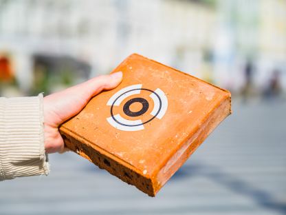 Ein gestalteter Ziegel, wie er bei der Eröffnung an die Pat:innen überreicht wird in der Hand einer Person. (Foto: Arman Kalteis)