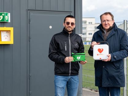 Sportbeauftragter Florian Gleiss und Bürgermeister Matthias Stadler mit dem neuen Defibrillator auf der Stadtsportanlage. (Foto: Christian Krückel)