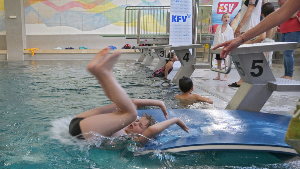 Ein Mädchen, das an einem Selbstrettungsschwimmtraining teilnimmt, springt in ein Schwimmbecken.