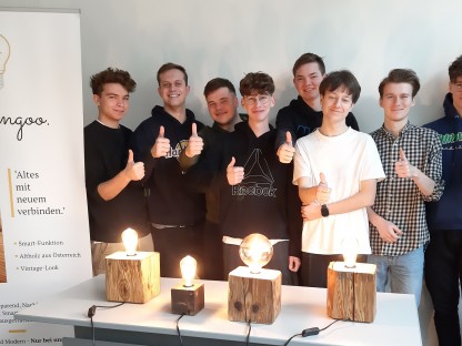 Werbeplakat daneben Tisch mit Tischlampen aus Holz mit Glühbirnen gefertigt dahinter stehen HTL Schüler (Foto: HTL St. Pölten