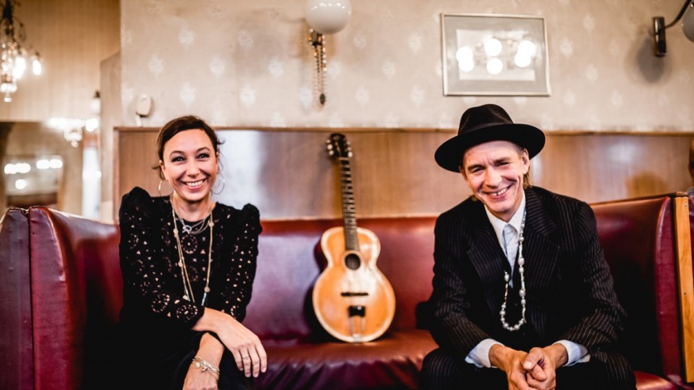 Ursula Strauss und Ernst Molden sitzend auf einer Couch. Im Hintergrund sieht man eine Gitarre. (Foto: Daniela Matejschek)