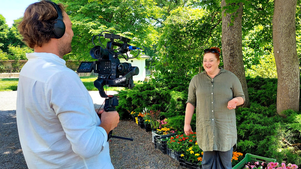 Veronika Polly plauscht im Garten der Musikschule, Bernhard Brunnthaler filmt.