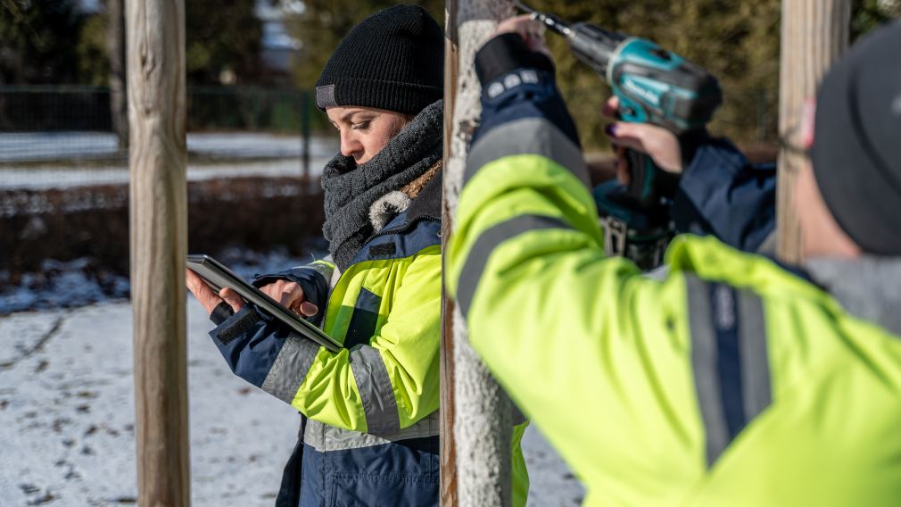 Eine Mitarbeiterin der Stadtgärtnerei schrauben Baum-Plaketten neu ein während eine zweite über ein Tablet die digitale Erfassung der Bäume aufruft. (Foto: Christian Krückel)