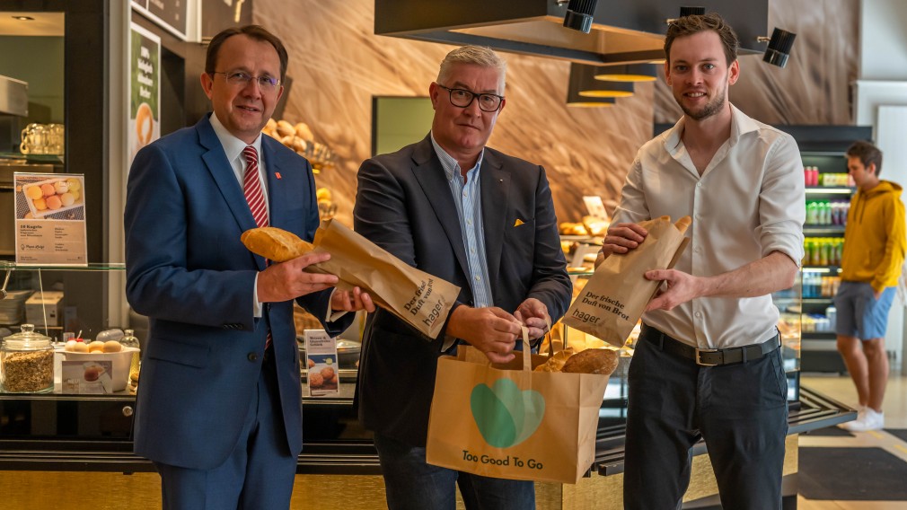 Bürgermeister Matthias Stadler, Hager-Geschäftsführer Wolfgang Hager und Georg Strasser, Geschäftsführer von „To Good to Go“-Austria stehen in der Bäckerei Hager und präsentieren das Too Good to Go-Überraschungssackerl.