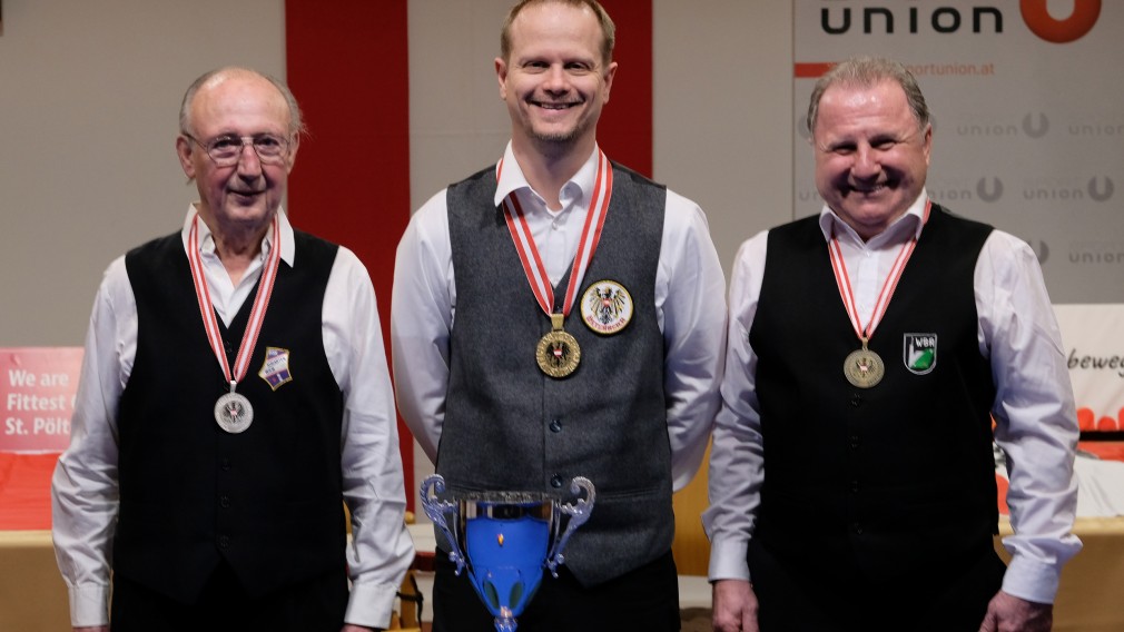 Drei Männer mit Medaille und Pokal vor Billardtisch