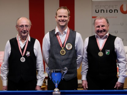 Drei Männer mit Medaille und Pokal vor Billardtisch