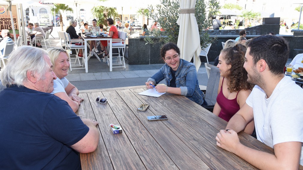 Zwei Männer und drei Frauen sitzen bei einem Tisch im Freien am Rathausplatz. (Foto: Josef Vorlaufer).