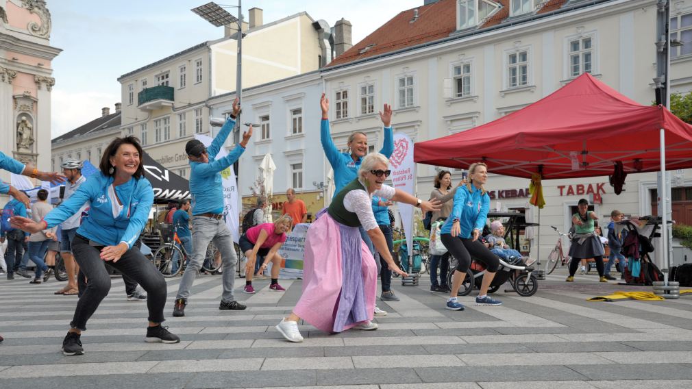 Ein Foto der BMX-Stunt-Show am Rathausplatz mit Publikum und den Infoständen der diversen Aussteller:innen. (Foto: Wolfgang Mayer)