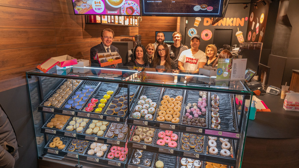 MitarbeiterInnen der neuen Dunkin‘ Donuts-Filiale bei einem Gruppenfoto mit Bürgermeister Matthias Stadler.