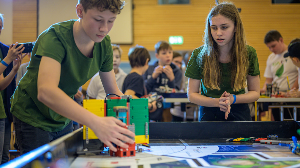 Zwei Mitglieder eines Teams vom BRG/BORG St. Pölten bedienen während des Wettbewerbs ihren Roboter.