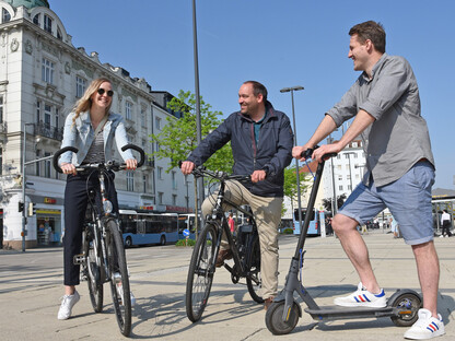 Drei Personen stehen mit Fahrrädern und einem Roller am Bahnhofplatz in St. Pölten. (Foto: Josef Vorlaufer)