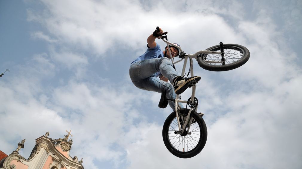 Ein Foto der BMX-Stunt-Show am Rathausplatz mit Publikum und den Infoständen der diversen Aussteller:innen. (Foto: Wolfgang Mayer)