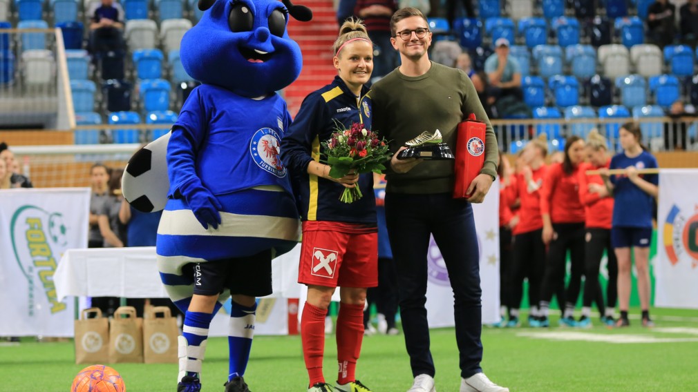 SKN Spielerin Isabelle Meyer bei Blumenübergabe mit Fußball Maskotchen auf Spielfeld