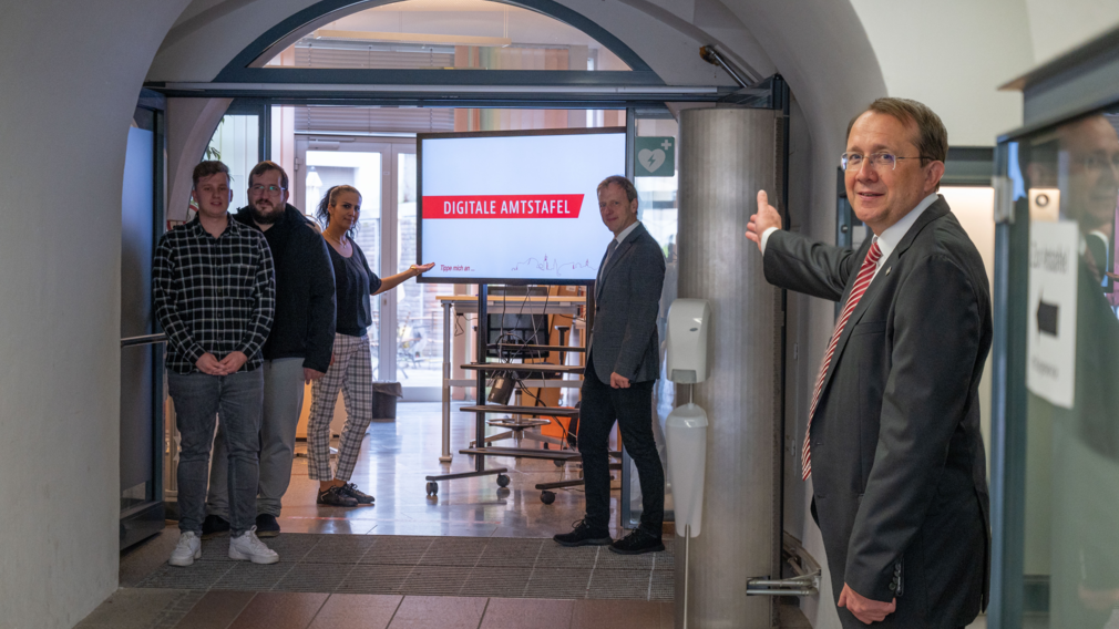 Bürgermeister Stadler zeigt in eines Bildschirm, auf dem die digitale Amtstafel betrieben wird.