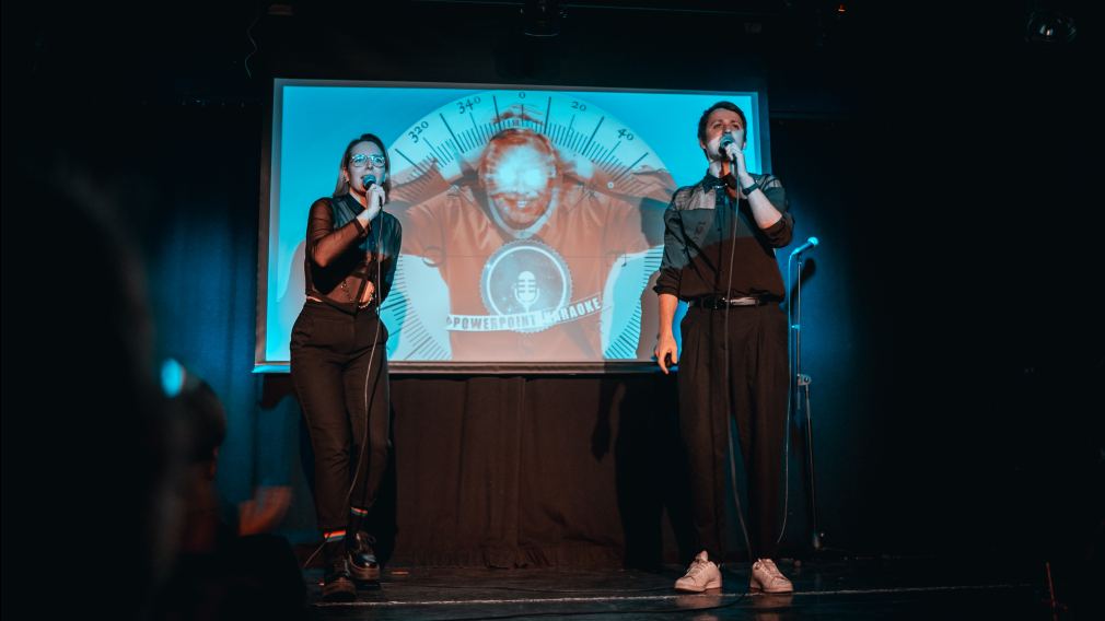 Zwei Personen stehen vor einer Powerpoint Präsentation auf einer Bühne. Foto: Petra Weixelbraun