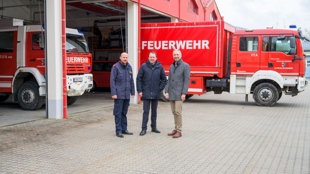 Drei Herren bei den Garagen der FF-Pottenbrunn, im Hintergrund stehen Feuerwehrfahrzeuge.