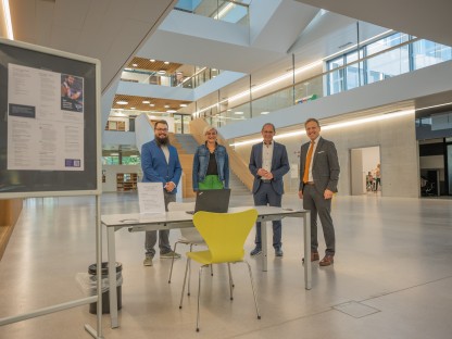 Vier Personen befinden sich im neuen Gebäude der Fachhochschule St. Pölten und lachen für ein Gruppenfoto in die Kamera.