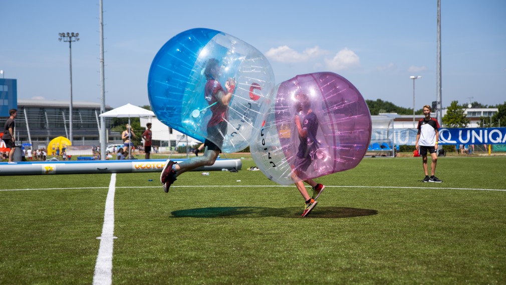 zwei Jugendliche hüpfen geschützt durch einen aufgeblasenen Ganzkörperball aufeinander zu (Foto: Andreas Simon)