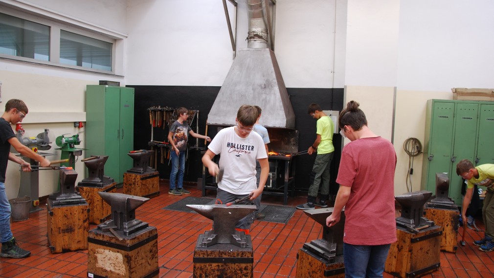 Sieben Jugendliche beim Schmieden in einer Werkstätte. (Foto: HTL St. Pölten).