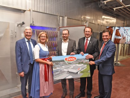 Vier Männer und eine Frau halten ein Schild in der Hand und positionieren sich für ein Gruppenfoto.