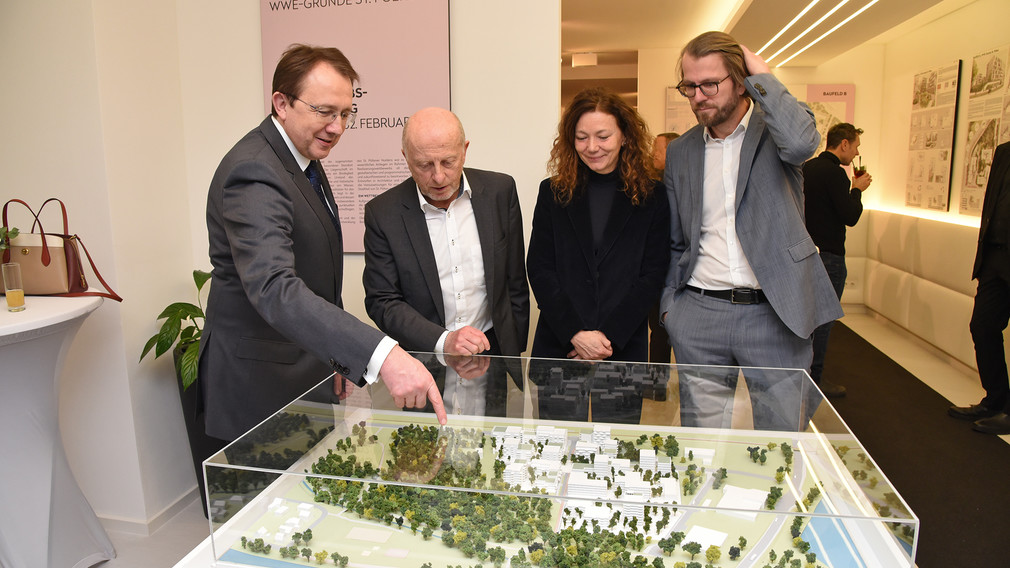 Vier Personen betrachten das Miniaturmodell der geplanten Wohnobjekte auf den WWE-Gründen bei der Ausstellung in der Kremser Gasse. (Foto: Josef Vorlaufer)