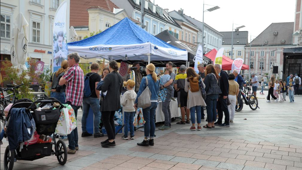 Ein Foto der BMX-Stunt-Show am Rathausplatz mit Publikum und den Infoständen der diversen Aussteller:innen. (Foto: Wolfgang Mayer)