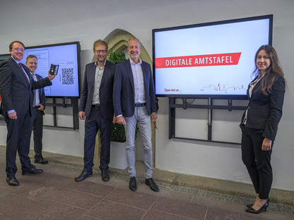 Fünf Personen vor der neuen, digitalten Amtstafel im Rathaus-Eingang. (Foto: Kalteis)