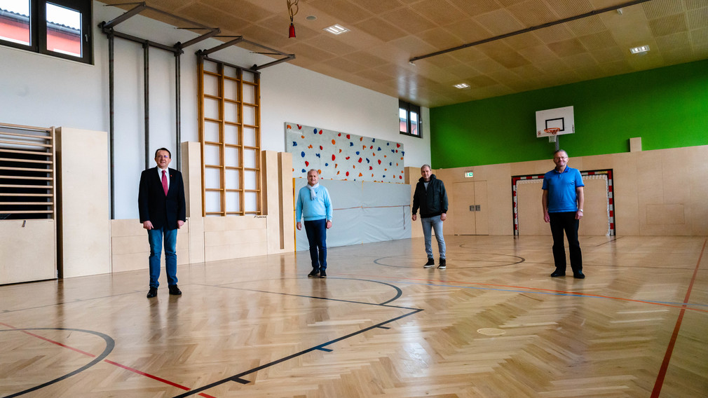 Vier Herren, darunter Bürgermeister Matthias Stadler, Schulamtsleiter Andreas Schmidt, Thomas Reichl, von der Immobiliengesellschaft der Stadt St. Pölten und Direktor der NMS Viehofen Hermann Reichebner, stehen in einem Schulturnsaal und blicken für eine Foto in die Kamera.