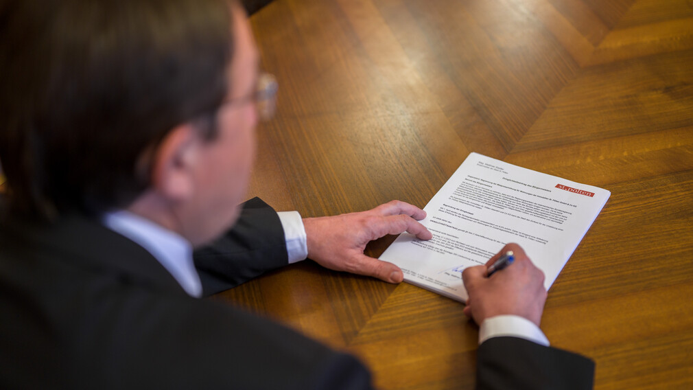 Bürgermeister unterzeichnet Antrag auf Schreibtisch. (Foto: Kalteis)