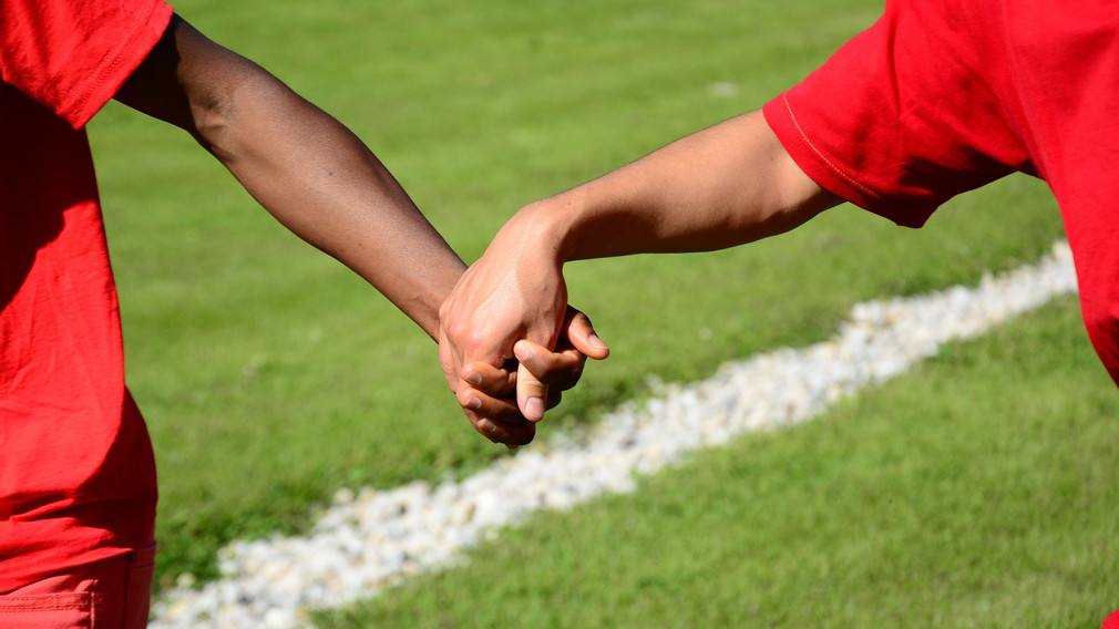 Kinder Hand in Hand am Fußballplatz. (Foto: Ulrich/pixabay)