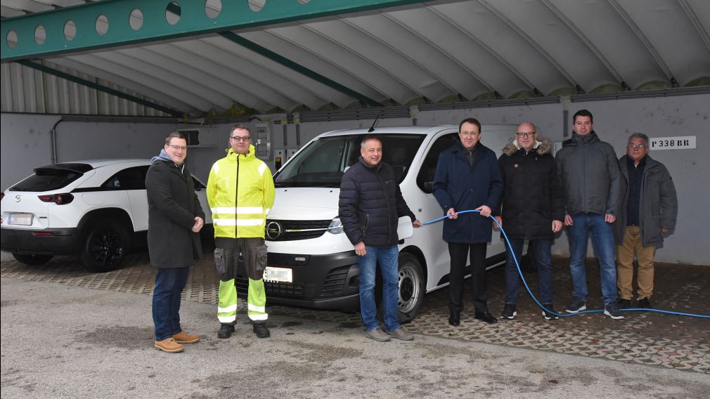 Sieben Personen posieren für ein Gruppenfoto vor einem Elektro-Auto, das an einer der neuen Ladestationen am Wirtschaftshof angesteckt ist. (Foto: Josef Vorlaufer)