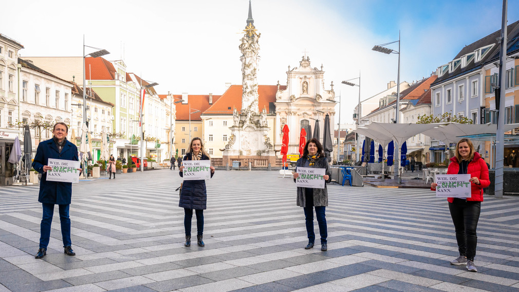 Bürgermeister Matthias Stadler, Claudia Pommer (Psychologin/Psychotherapeutin) , Mirsada Zupani (Sozialarbeiterin und Case Management) und Nihada Kotoucek (Psychotherapeutin) stehen am Rathausplatz mit einem Plakat auf dem steht: Weil die Gesundheit nicht warten kann. Foto: Arman Kalteis