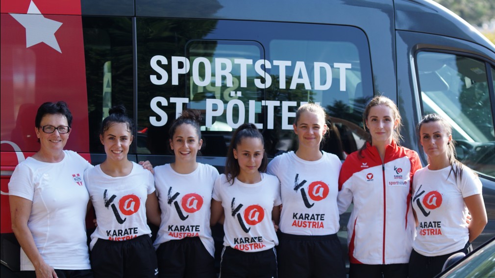 Karathe-Sportlerinnen posieren vor dem Sportbus der Stadt St. Pölten