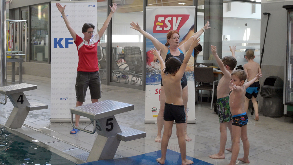 Ein Mädchen, das an einem Selbstrettungsschwimmtraining teilnimmt, springt in ein Schwimmbecken.