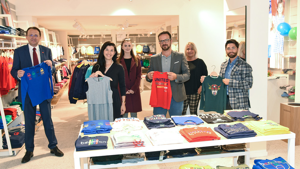 Bürgermeister Matthias Stadler und Vertreter der Stadt sowie die Betreiber des neuen Benetton-Store mit Kleidungsstücken im Geschäftslokal. (Foto: Vorlaufer)