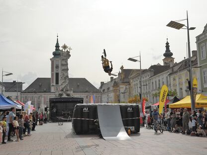 Ein Foto der BMX-Stunt-Show am Rathausplatz mit Publikum und den Infoständen der diversen Aussteller:innen. (Foto: Wolfgang Mayer)