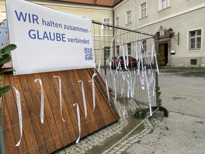 Weiße Bänder mit Friedensbotschaften hängen an einem Bauzaun. Foto: Diözese St. Pölten