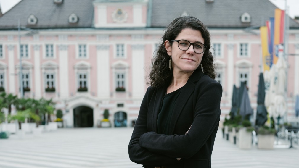 Angelika Schopper an einem Stein lehnend vor dem Rathaus