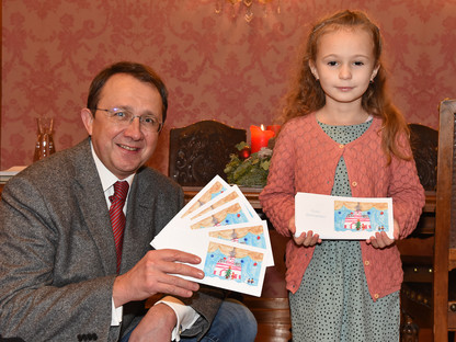 Bürgermeister Stadler und Emilia Schöne präsentieren die Weihnachtskarte mit Emilias Zeichnung.