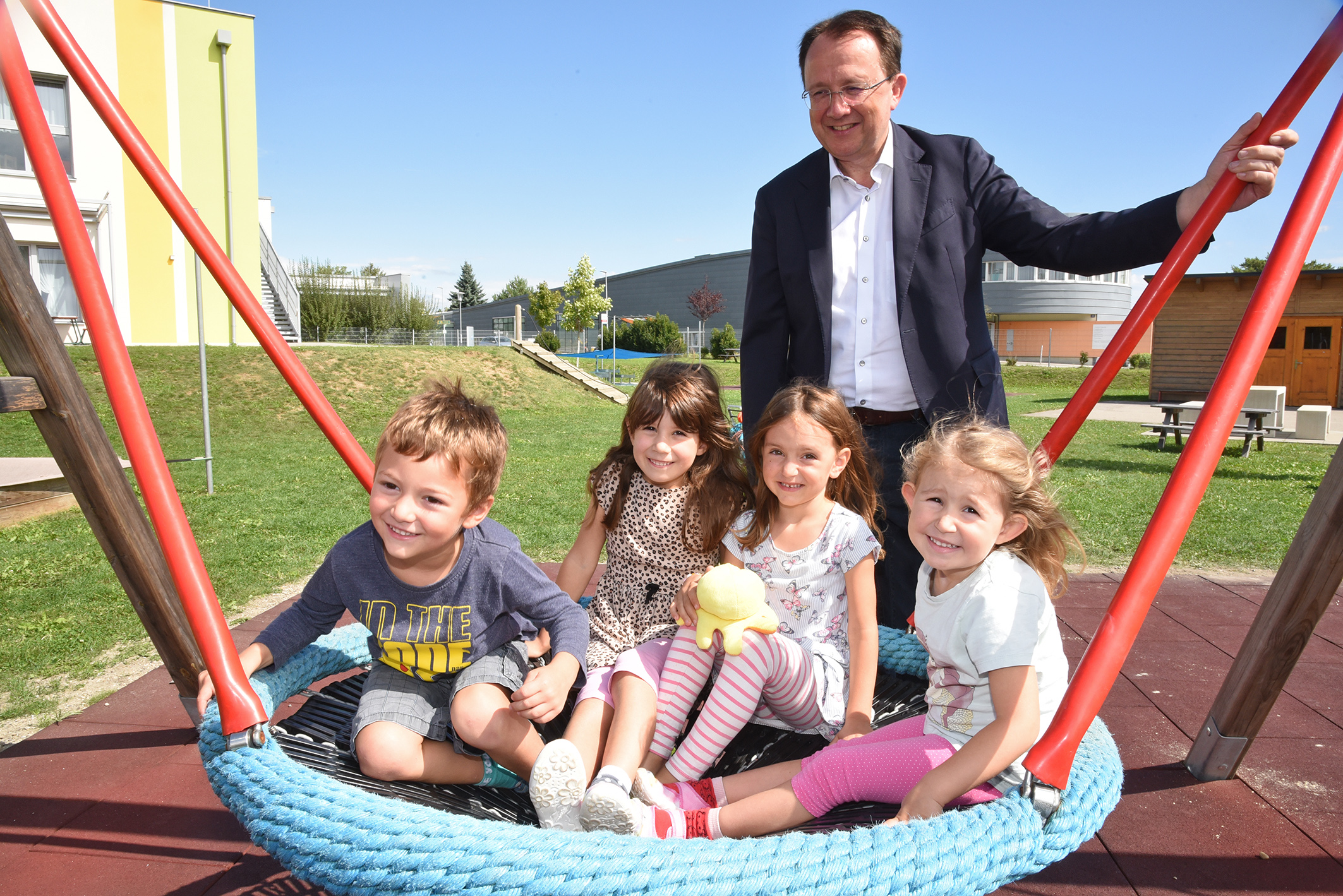 Das Foto zeigt Bürgermeister Matthias Stadler und 4 Kinder auf einer Schaukel.