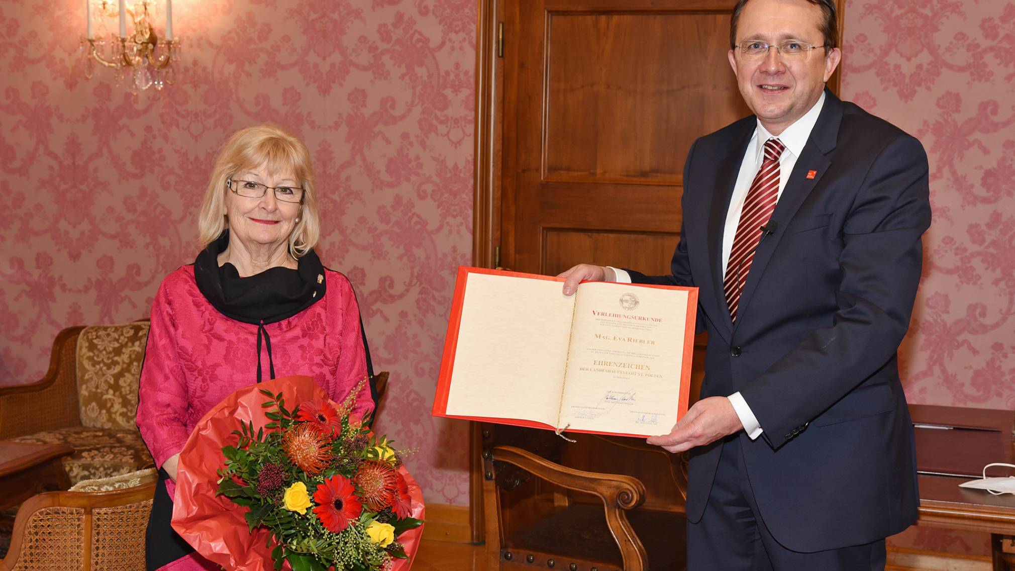 Bürgermeister Matthias Stadler hält Urkunde, Eva Riebler-Übleis hält einen Blumenstrauß. Beide stehend im Bürgermeisterzimmer. (Foto: Josef Vorlaufer)